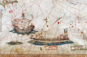 Questa immagine è un dettaglio della Carta Nautica del Mediterraneo creata nel 1482 dall’italiano Grazioso Benincasa.La scena mostra due tipi di navi genovesi dell’epoca: una galea (nave a remi) in primo piano e una caravella portoghese sullo sfondo. Le linee rosse sullo sfondo sono linee di rotta (losodromiche), tipiche dei portolani medievali per facilitare la navigazione. L’originale di questa pergamena miniata è conservato presso la Biblioteca Universitaria di Bologna.