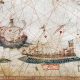Questa immagine è un dettaglio della Carta Nautica del Mediterraneo creata nel 1482 dall’italiano Grazioso Benincasa.La scena mostra due tipi di navi genovesi dell’epoca: una galea (nave a remi) in primo piano e una caravella portoghese sullo sfondo. Le linee rosse sullo sfondo sono linee di rotta (losodromiche), tipiche dei portolani medievali per facilitare la navigazione. L’originale di questa pergamena miniata è conservato presso la Biblioteca Universitaria di Bologna.